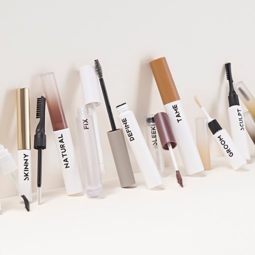 A lineup of HCP's ‘Tame & Frame’ precision grooming tools, showcasing a variety of applicators and packaging designs labeled FEATHER, SKINNY, NATURAL, FIX, DEFINE, SLEEK, TAME, GROOM, SCULPT, and STYLE for brows, beards, and hairline styling.